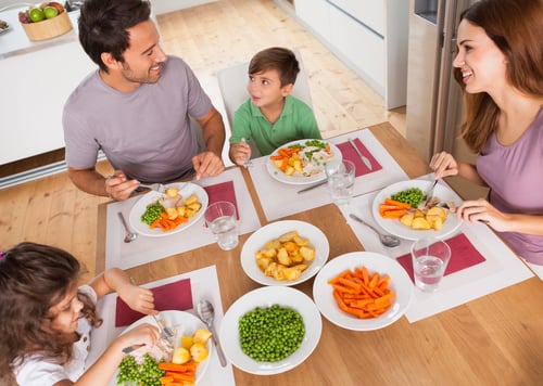 Family smiling around a healthy meal in kitchen